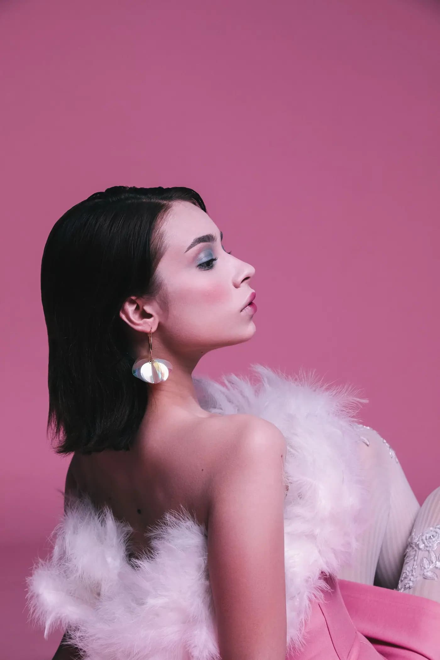 Mujer con vestido rosa y plumas sobre fondo rosa